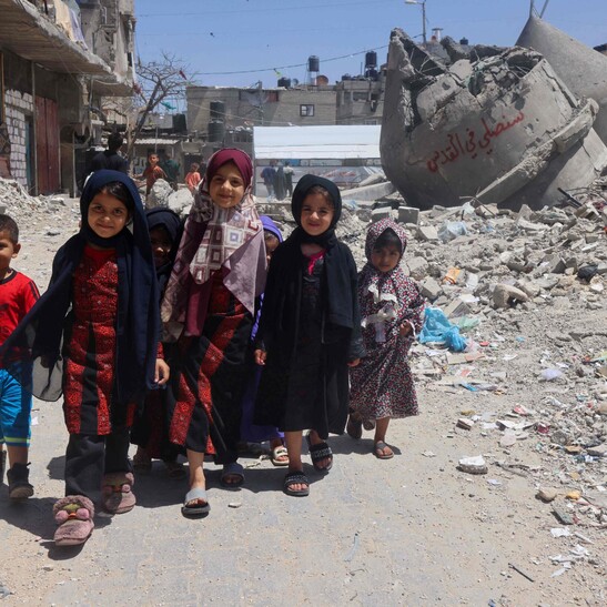 Crianças palestinas caminham perto de ruína de mesquita destruída por Israel em Rafah